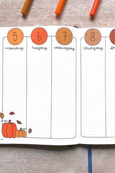 an open planner with pumpkins and numbers on it, next to some crayon markers