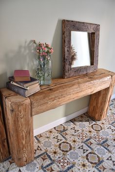 a wooden bench sitting next to a mirror on top of a tiled floor near a vase with flowers