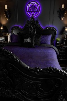 a bed with purple comforter and black headboard in front of a neon sign