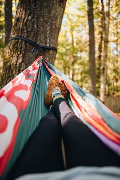 a person laying in a hammock with their feet up on the ground next to a tree