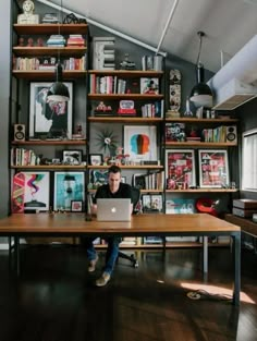 a man sitting at a table with a laptop in front of him, surrounded by bookshelves