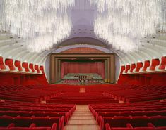 an empty auditorium with red seats and chandeliers