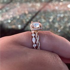 a close up of a person's hand holding an engagement ring with diamonds on it