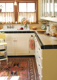 a kitchen filled with lots of counter top space and white cabinets next to a window