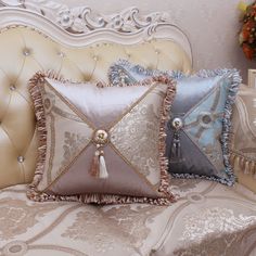 two pillows with tassels on them sitting on a couch next to a pillow