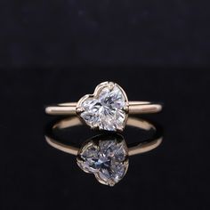 an engagement ring with two heart shaped diamonds on the front and side, sitting on a black surface