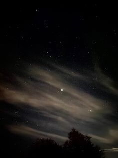 the night sky is filled with stars and clouds, as well as some dark trees