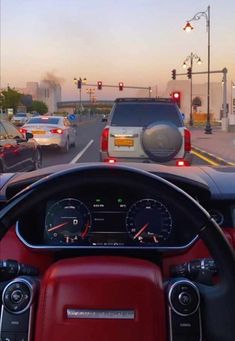 the dashboard of a car on a busy street with traffic lights and cars driving down it