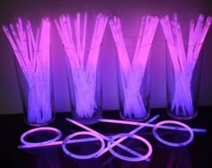 four clear vases filled with purple lite up straws next to each other