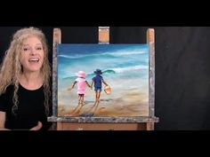 a woman standing next to an easel with a painting on it's side