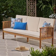 a wooden bench sitting on top of a rug next to a tree and shrubbery