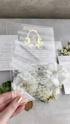 the wedding stationery is displayed in clear acrylic with white flowers and greenery