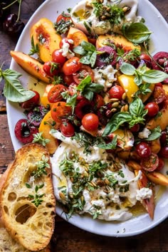 a white plate topped with fruit and vegetables next to a baguette bread on top of a wooden table