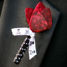 a red heart shaped brooch sitting on top of a black suit lapel cover