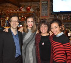 three women and one man are posing for a photo in front of the bar counter