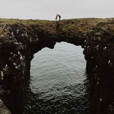 two people standing on the edge of a bridge over water