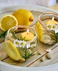 two lemons and some white flowers are in small glass bowls with water on a wooden table