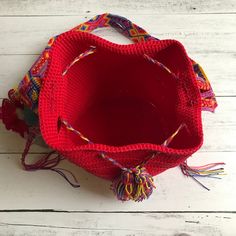 a red bag with tassels on it sitting on top of a white wooden floor