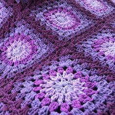 a crocheted blanket with purple and white flowers