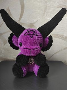 a purple and black stuffed animal with horns on it's head sitting on a table