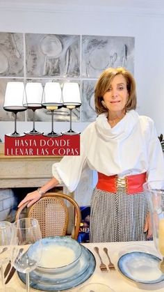 a woman standing in front of a table with plates and glasses on it