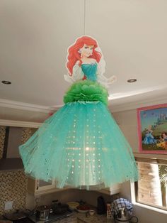 a green dress hanging from the ceiling in a kitchen with an image of ariel on it