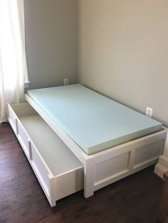 a white bed frame with drawers underneath it