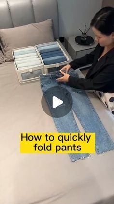 a woman sitting on top of a bed next to two pairs of blue jean pants