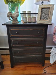 a black dresser with flowers in a vase and other items on the top shelf next to it