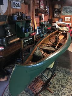 a green canoe sitting on top of a wooden floor next to a desk and shelves