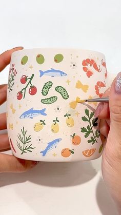 someone is using scissors to cut out the side of a cup with fish and berries on it