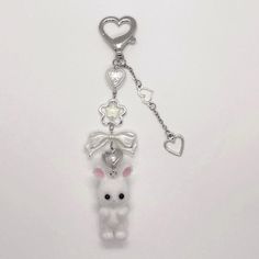 a keychain with a white teddy bear and heart charms on it's side