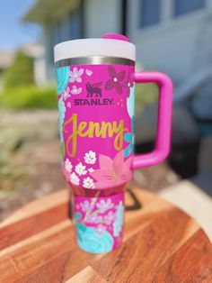 a pink and blue travel mug sitting on top of a wooden table