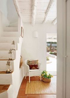 a white chair sitting on top of a wooden floor next to a stair case and potted plant