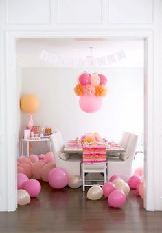 a dining room with balloons and table in the middle, along with pink and orange decorations