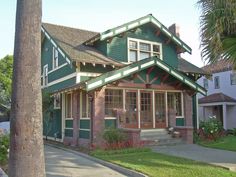 a green and red house on the corner of a street with palm trees in front of it