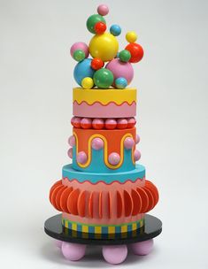 a multi - colored cake with balloons on top is shown in front of a white background