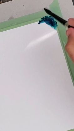 someone is using a brush to paint the bottom of a piece of paper with blue and green crayons