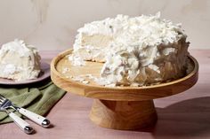 a cake with white frosting sitting on top of a wooden plate next to a knife and fork