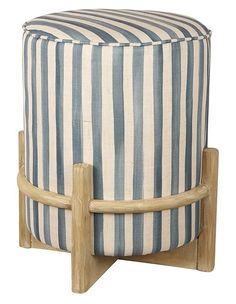 a blue and white striped ottoman sitting on top of a wooden stand next to a wall