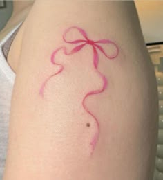 a woman's arm with pink ink on it and a bow around the wrist