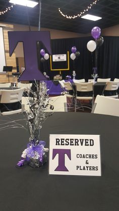 a table topped with purple and white balloons next to a sign that says reserved coaches & players