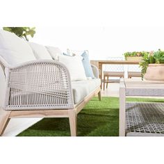 an outdoor living room with white wicker furniture and green carpeted area rugs