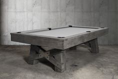 a pool table in an empty room with concrete walls and flooring on either side