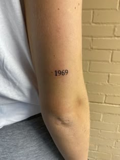 a woman with a small tattoo on her arm that reads,'nineteen nine year old