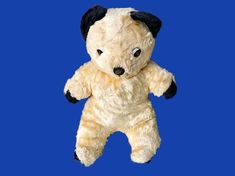 a teddy bear with black ears and eyes on a blue background