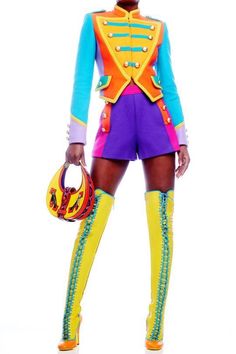 a woman in brightly colored clothes holding a handbag and wearing yellow knee high boots