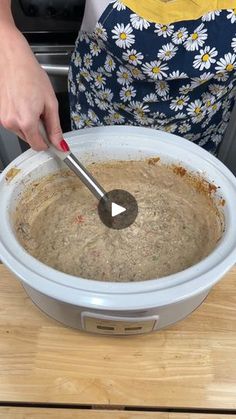 a woman is mixing food in a crock pot