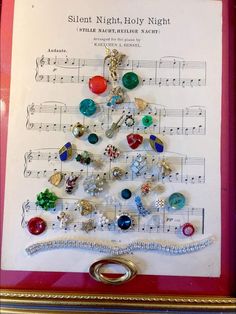 a christmas tree made out of buttons and other items on a sheet of music paper