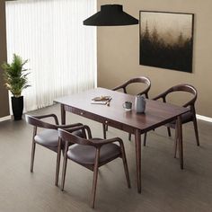 a dining room table with four chairs and a potted plant in the corner next to it